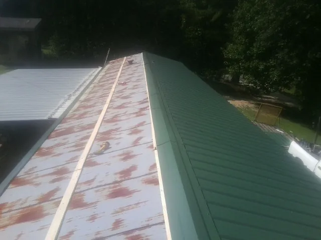 Old rusted panels beside newly installed green metal roofing — Wind Damage Roof Repair by Roofing Brothers in Terryville