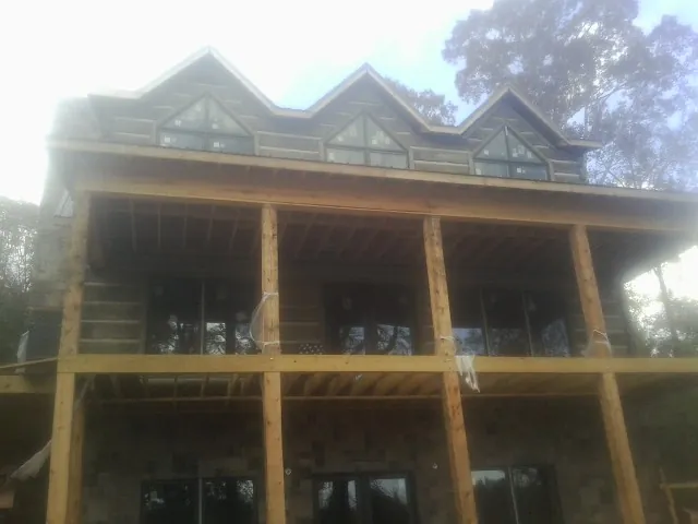 Dormers and porch framing on a large log home under construction — Roof Coating work by our crew in Terryville