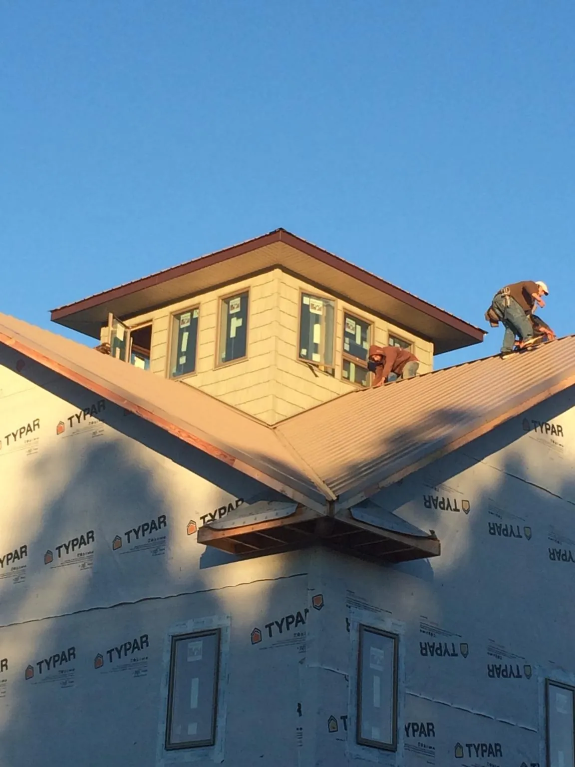 Roofers working around a rooftop cupola on a new metal roof at sunset — Roof Waterproofing in Terryville by Roofing Brothers